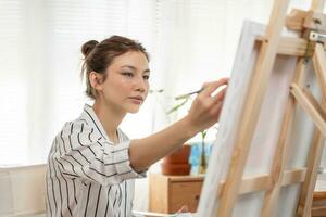 bellissimo femmina Hobby di artista e uso pennello nel astratto arte per creare capolavoro. pittore dipingere con acquerelli o olio nel studio Casa. godere pittura come passatempo, ricreazione, ispirazione foto