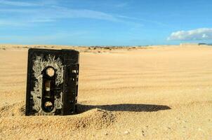 un vecchio cassetta nastro seduta nel il sabbia foto