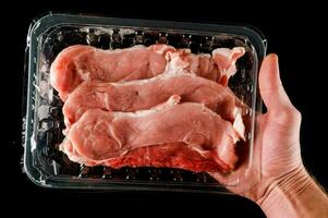 un' persona Tenere un' plastica contenitore con crudo carne foto