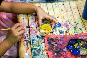 primo piano mani di studenti d'arte che tengono lo studio del pennello e l'apprendimento della pittura su legno bambola animale nell'aula d'arte. foto