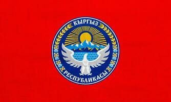 bandiera e cappotto di braccia di kirghiso repubblica su un' strutturato sfondo. concetto collage. foto