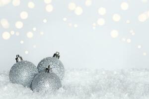 argento luccichio Natale ornamenti su letto di neve su bianca sfondo con bokeh effetto. copia spazio foto