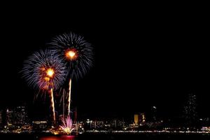 molti fuochi d'artificio lampeggianti con sfondo paesaggio urbano notturno capodanno. foto