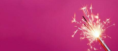 luminosa ardente sparkler bastone su rosa sfondo striscione. creare ai foto