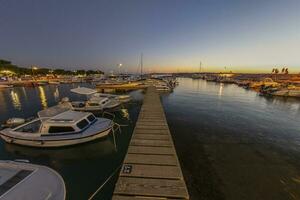 tramonto nel il porto di il croato costiero villaggio di fasana al di sopra di un' molo per Barche nel estate sera foto