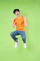 giovane uomo asiatico che salta, isolato su sfondo verde foto