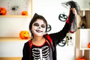 ritratto bambina asiatica in costume di halloween che tiene il teschio