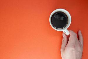 mani maschili tengono una tazza di caffè americano caldo su una pianura luminosa foto