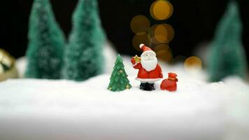 Natale giocattolo su ghirlanda sfondo. giocattolo Santa Claus su il sfondo di leggero lampadine. Natale sfondo Santa Claus con un' regalo. foto