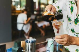 barista scrosciante caffè in bicchiere amnking ghiacciato caffè per cliente. foto