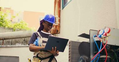 certificato tecnico Lavorando su all'aperto HVAC sistema, Tenere il computer portatile. competente meccanico ottimizzazione esterno aria condizionatore prestazione, garantendo esso opera a massimo capacità foto