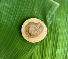 il giro di legno sottobicchiere piattaforma tavola isolato su superiore di verde strutturato Banana le foglie sfondo, sfondo, o sfondo. Tatakan Kayu, daun pisang. vuoto copia spazio. foto