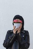 bellissimo medio orientale ragazza Tenere decorativo cestino pieno di fiori. carino arabo musulmano donna ricevuto unico fiore mazzo come presente per compleanno foto