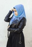 avvicinamento ritratto di bellissimo iraniano ragazza con blu occhi. attraente musulmano donna nel hijab copertura sua viso con sciarpa foto