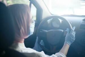 musulmano donna nel viso maschera e guanti guida auto foto