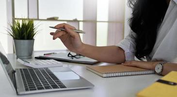 donna che tiene una penna in mano che punta allo schermo di un laptop.