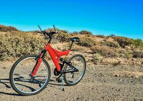 un' rosso bicicletta è parcheggiata su il lato di un' sporco strada foto