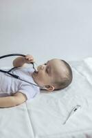 poco carino bambino medico. 6 mesi vecchio bambino ragazzo giocando con stetoscopio. ragazzo avendo divertimento piace un' medico foto