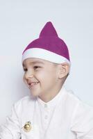 ritratto di un' sei anni ragazzo contro il bianca sfondo. festeggiare Natale. 6-7 anno vecchio ragazzo con Santa cappello. foto