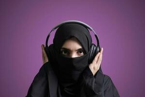 musulmano donna nel hijab ascoltando per musica con senza fili cuffia foto