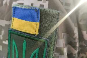 avvicinamento struttura pixel camuffare militare uniforme di il armato forze, gallone tridente e bandiera di Ucraina foto