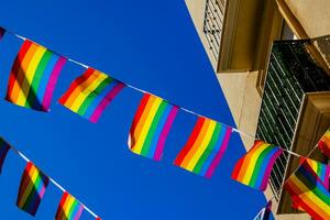 piccolo arcobaleno bandiera contro il cielo nel un' spagnolo città foto