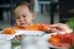 carino 5-6 mese asiatico bambino ragazza non lo fa volere per mangiare anguria foto