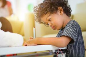 asiatico ragazzo utilizzando un' Magia penna per scrittura su taccuino e pomeriggio leggero foto