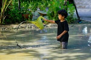 asiatico ragazzo giocando con fango nel un' divertimento posto dentro un' fango fossa costruito per bambini per giocare insieme. foto