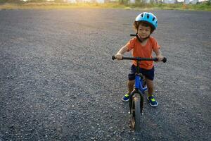 asiatico ragazzo primo giorno giocare equilibrio bicicletta. foto