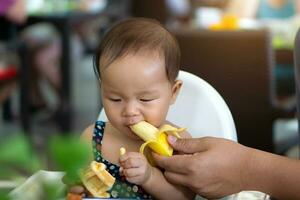 carino asiatico bambino piccolo bambino ragazza mangiare Banana foto