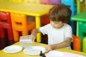 3 anno vecchio bambini nel Asia siamo conduzione scientifico esperimenti. foto