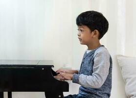 asiatico ragazzo apprendimento pianoforte nel il aula. foto