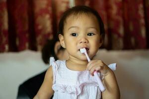 11 mesi ragazza praticante un' spazzolino di se stessa a partire dal sua La madre di insegnamento. foto