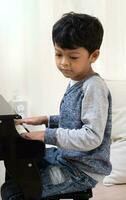 asiatico ragazzo apprendimento pianoforte nel il aula. foto