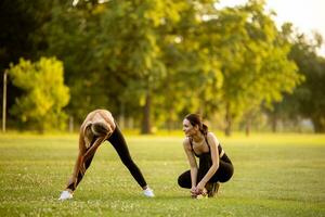 Due bella giovane donne allungamento nel il parco foto