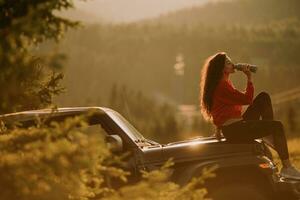 giovane donna che si rilassa su un cofano di un veicolo fuoristrada in campagna foto