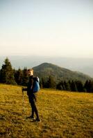 giovane uomo a piedi con zaino al di sopra di verde colline foto