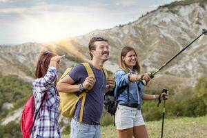 gruppo di giovane escursionisti a piedi verso il orizzonte al di sopra di il montagna foto