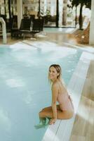 giovane donna rilassante di il interno nuoto piscina foto