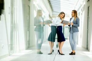 Due giovane attività commerciale donne con digitale tavoletta nel il ufficio corridoio foto