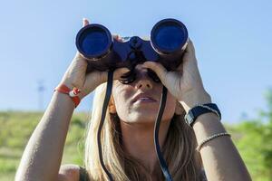 bella ragazza con il binocolo guardando l'orizzonte foto