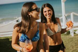 sorridente giovane donne nel bikini godendo vacanza su il spiaggia foto