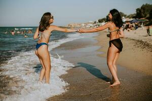 Due bella giovane donna avendo divertimento su il mare foto