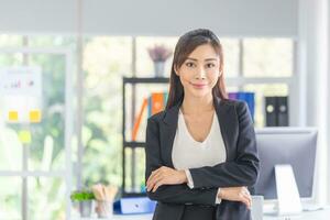 attività commerciale donna con braccia attraversato, ritratto sorridente donna in piedi nel moderno ufficio con braccia attraversato foto