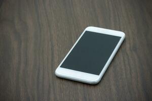inteligente Telefono nel bianca colore con vuoto schermo su di legno tavolo. foto