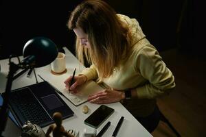 femmina progettista Lavorando nel casa ufficio a notte foto