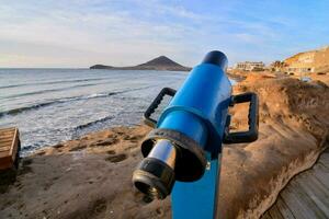 un' blu telescopio su il spiaggia con il oceano nel il sfondo foto