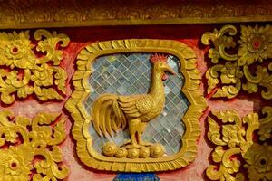 un' Gallo è su un' oro parete nel un' tempio foto