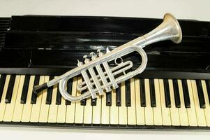 un' argento tromba su superiore di un' pianoforte tastiera foto